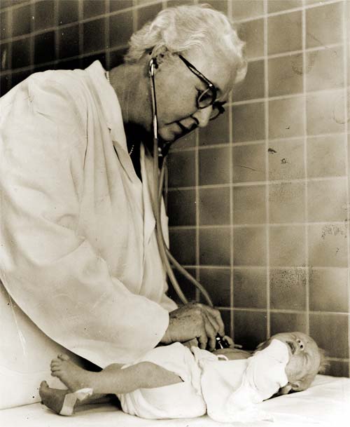 Virginia Apgar untersucht ein neugeborenes Baby